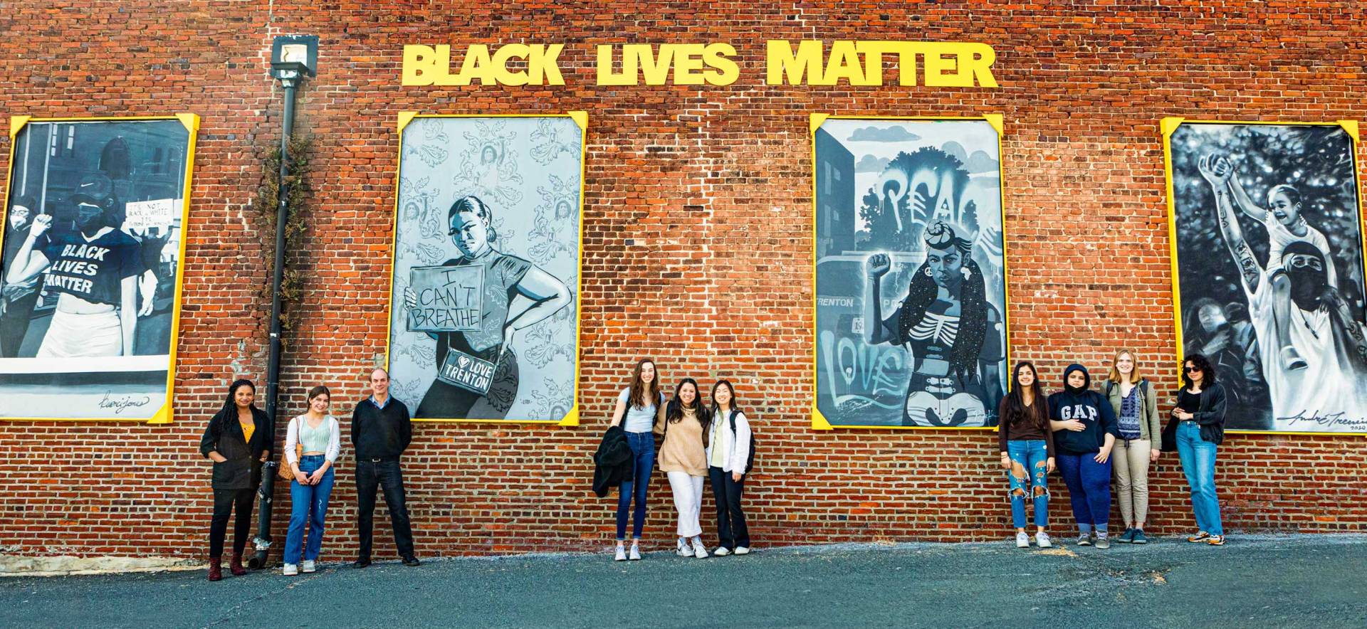 Professors and students pose in front of large scale artwork
