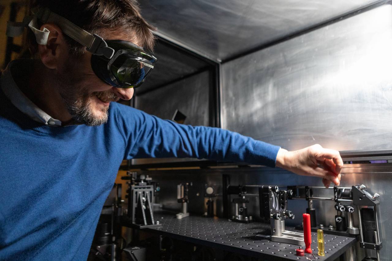 A man in loupe goggles tightens a tiny bolt with a pin-sized Allen wrench.