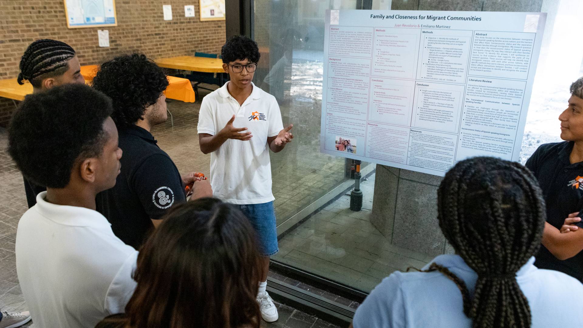 Students gather around a student presenting a research poster