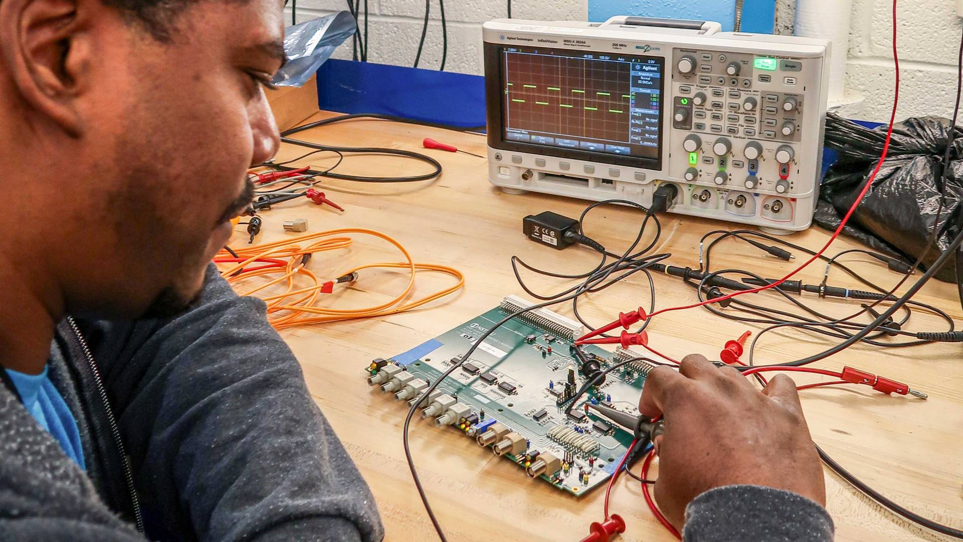 An apprentice works on a circuit board