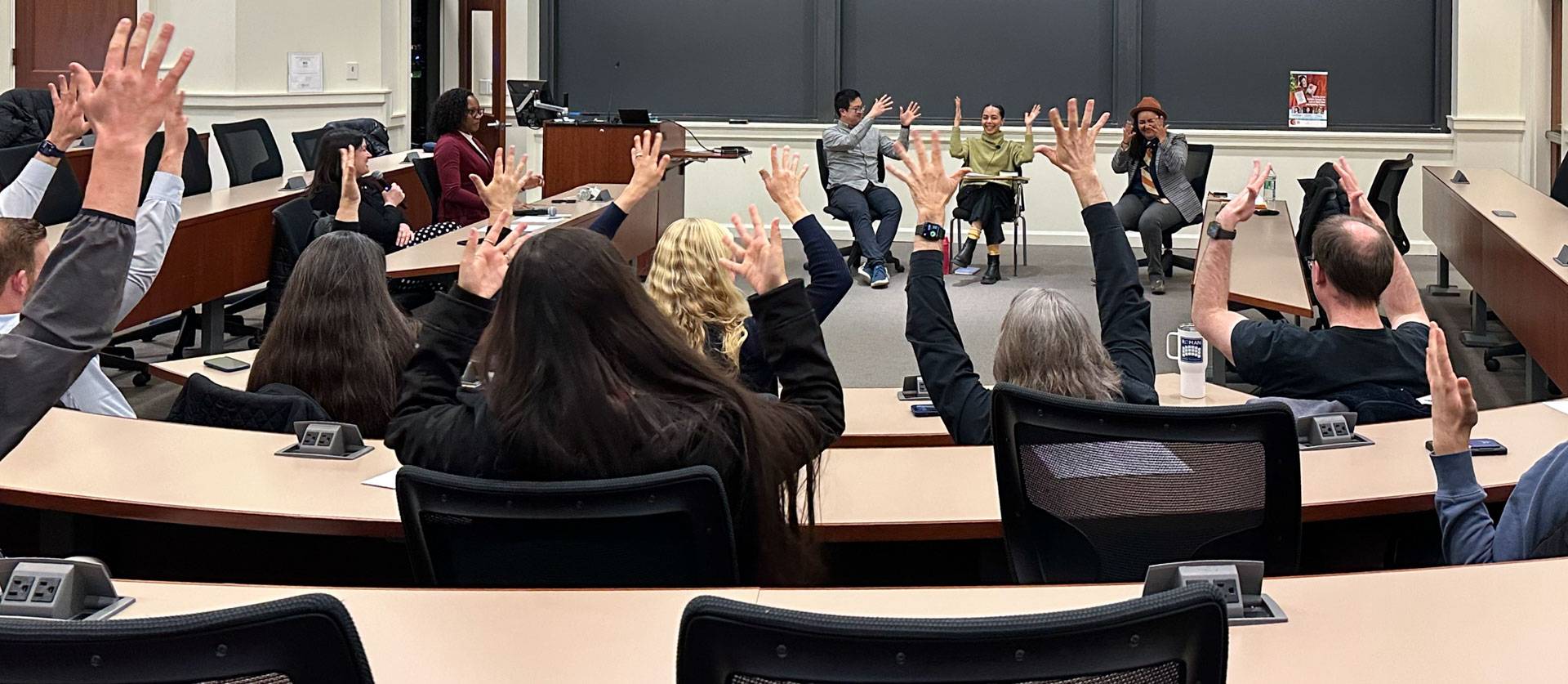A room full of people using American Sign Language to convey their applause.