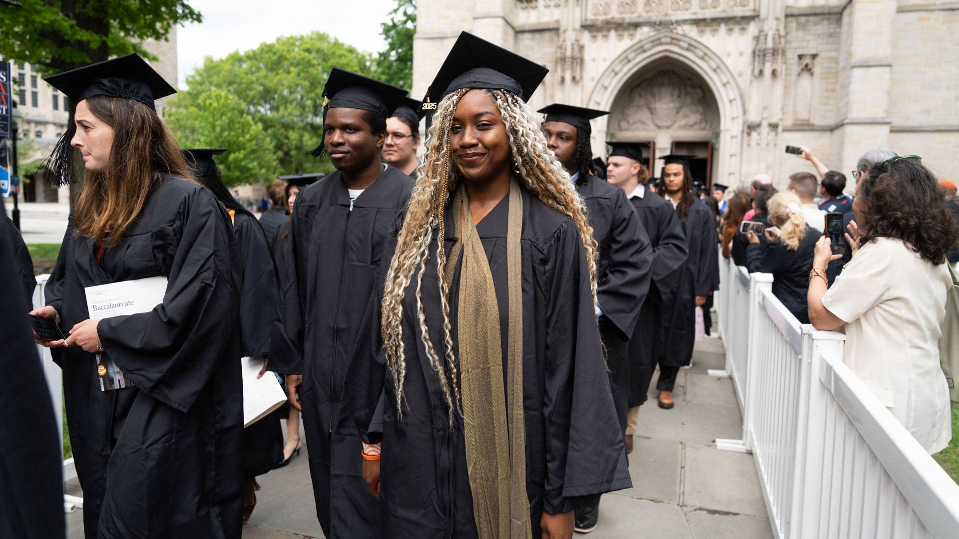 Students in graduation regalia walk out of the Chapel.