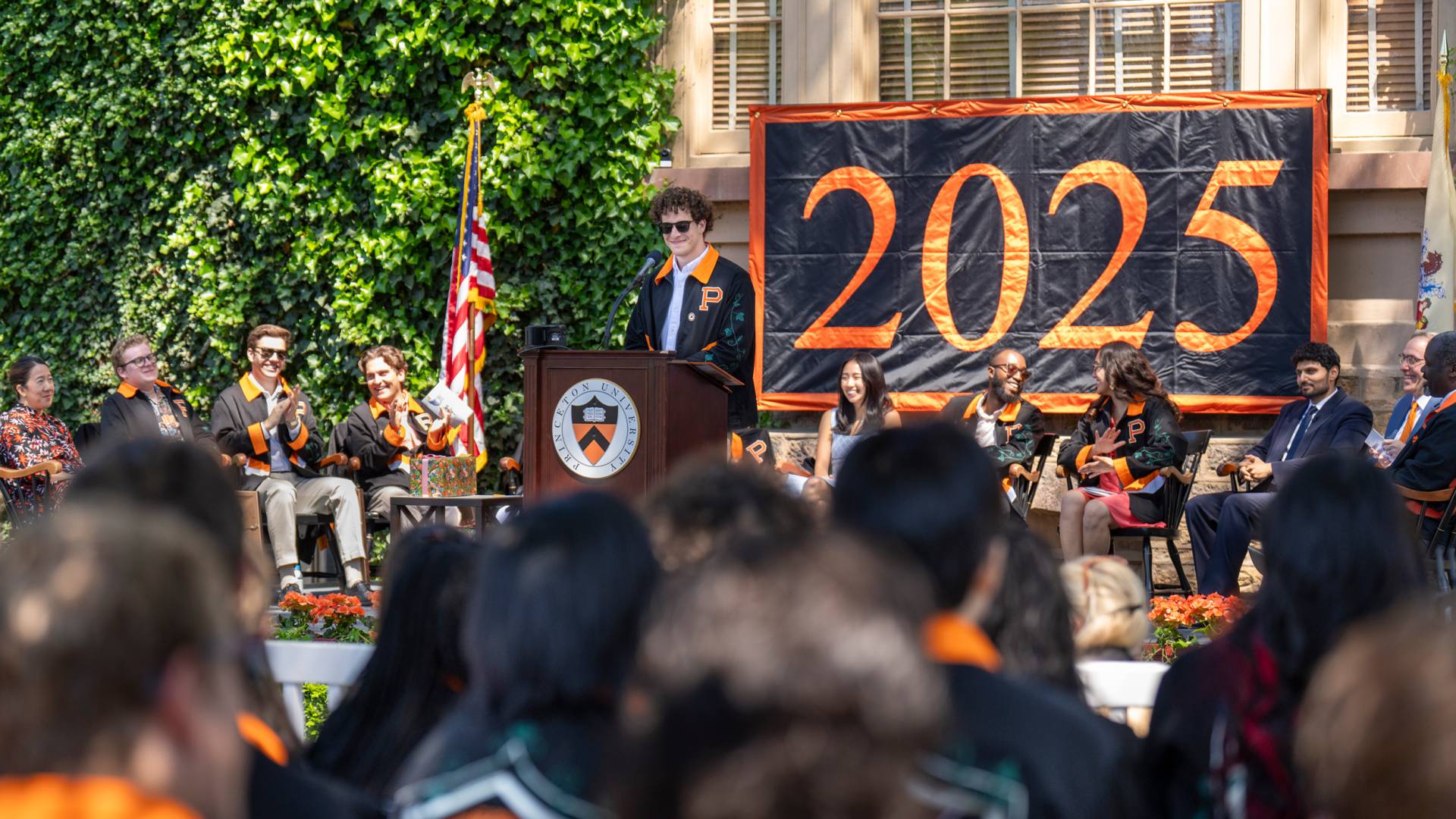 Class president Ben Wachspress on the Class Day stage, with a prominent 2025 banner behind him.