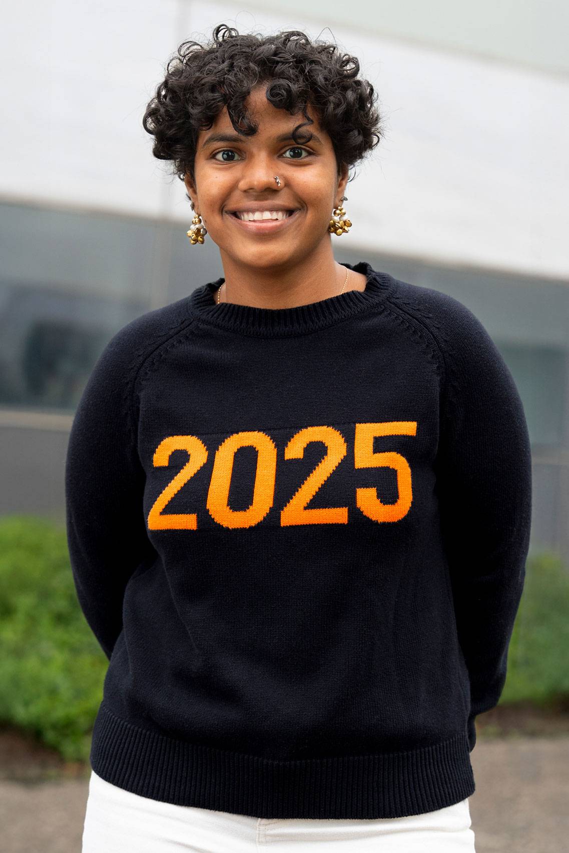 Kajal Schiller stands outside wearing a "Class of 2025" sweatshirt.