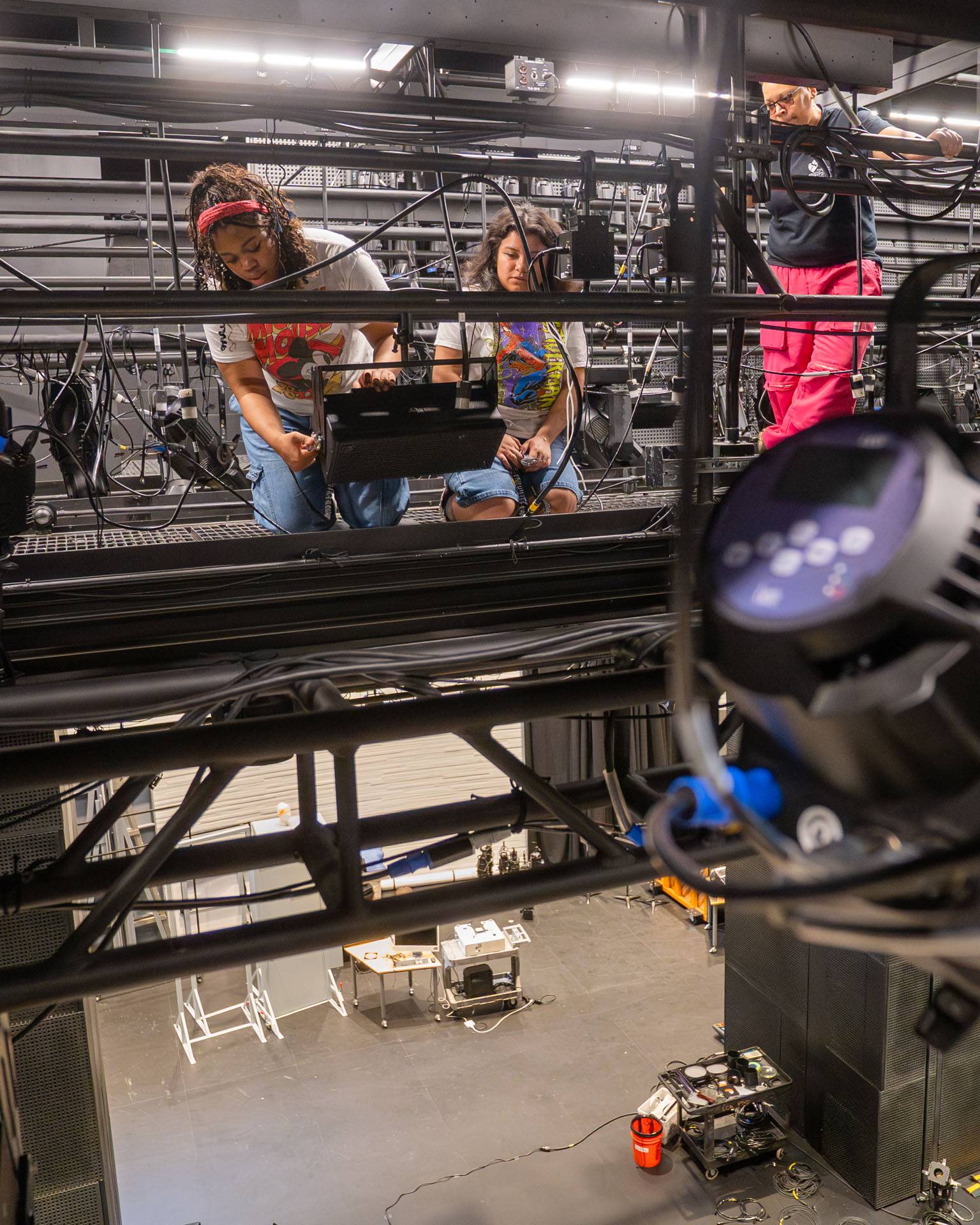 Students hang a speaker as sound supervisor Kay Richardson looks on.