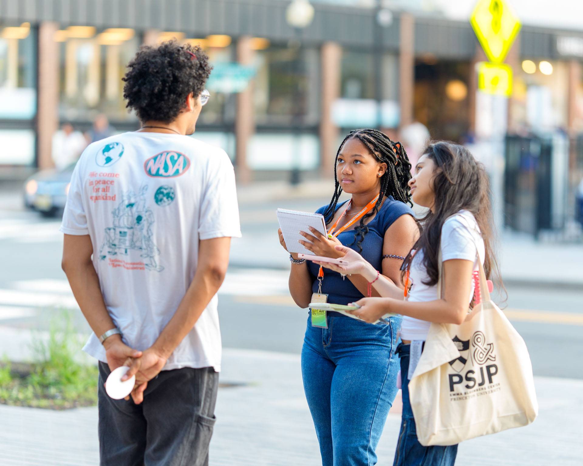 Two students in PSJP gear interview a person on the streets of downtown Princeton