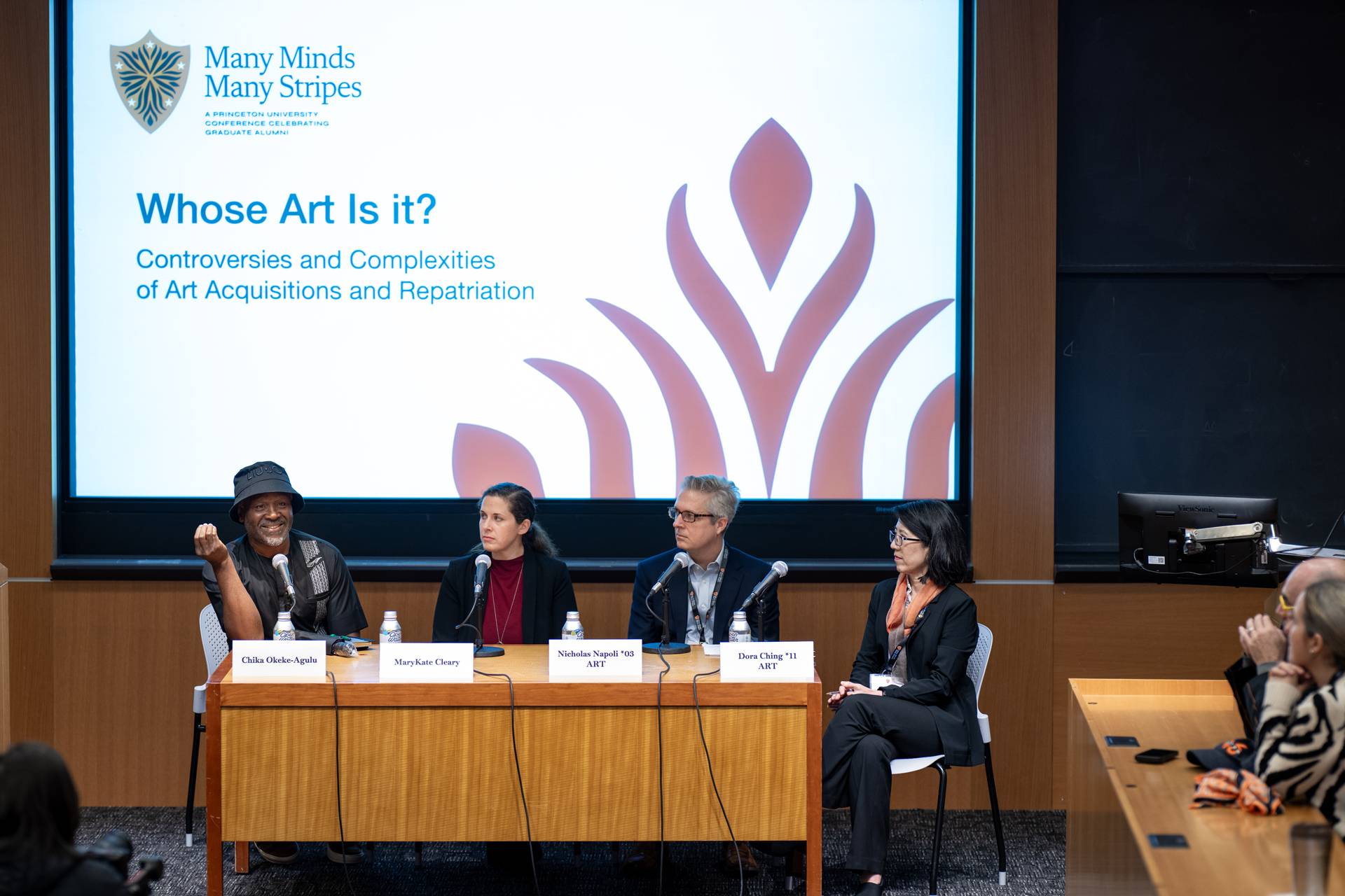 Four panelists seated on stage address the audience and each other.