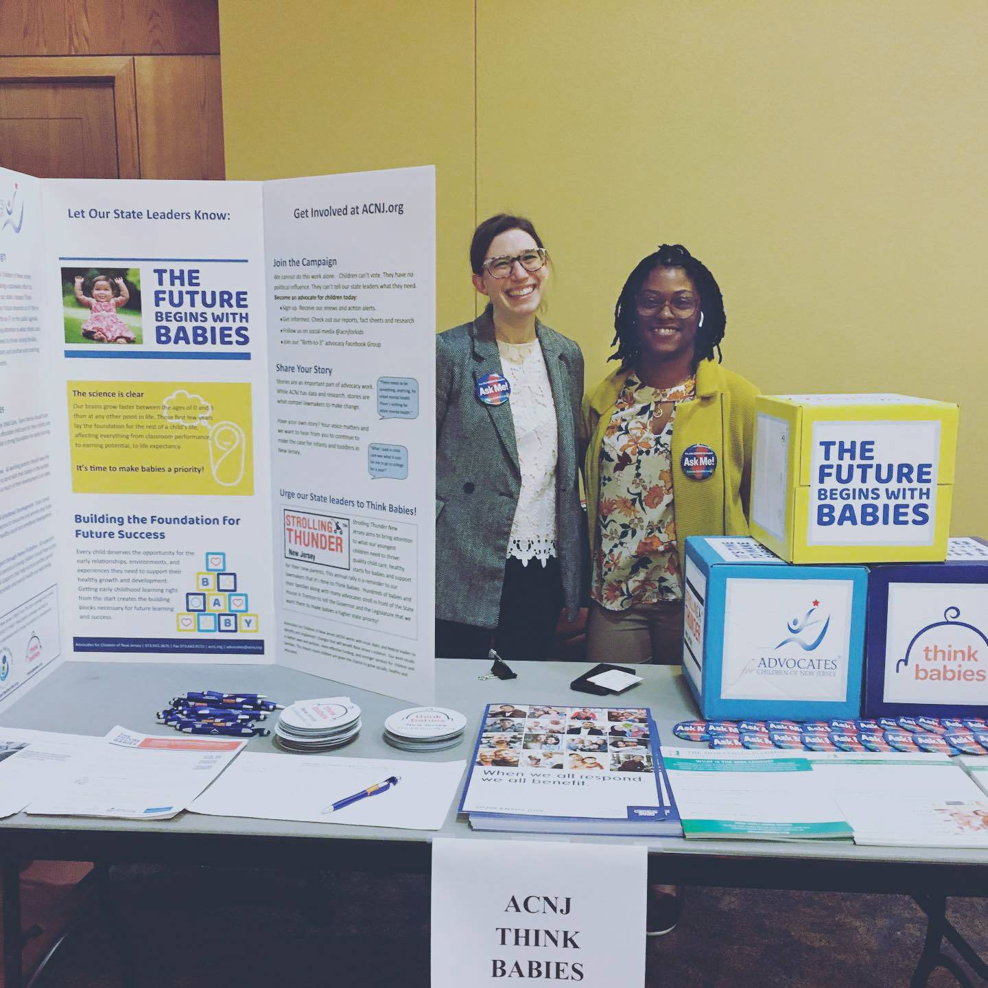 Two people stand behind an infant care information booth