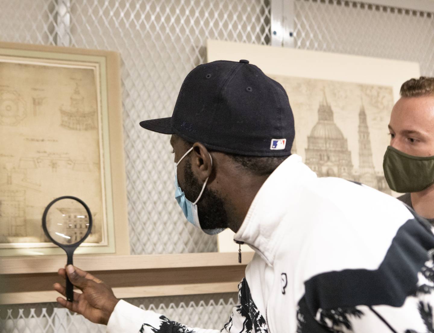 A student looks at artwork with a magnifying glass.