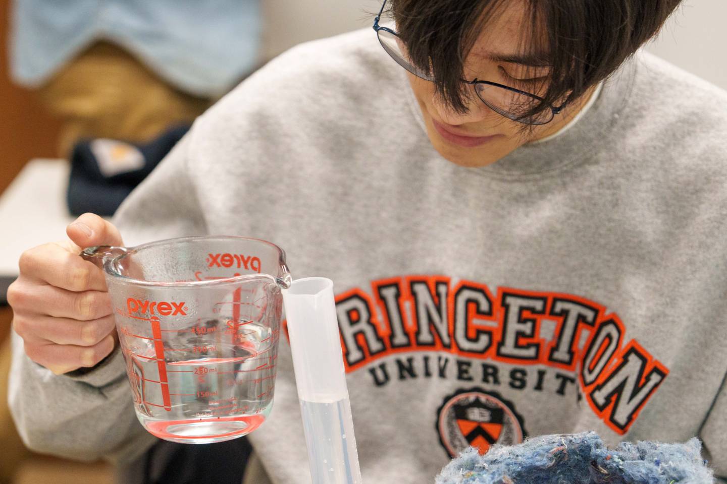 A student carefully pours liquid in a tube.