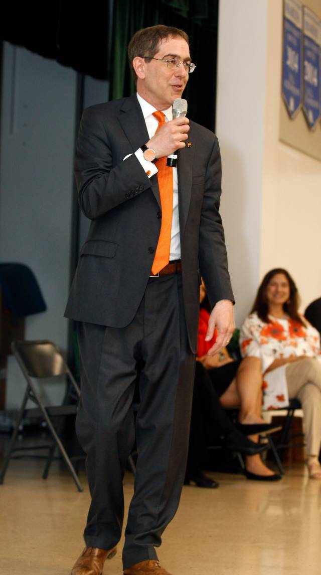 Christopher L. Eisgruber stands on stage with a microphone, speaking